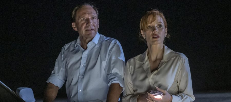 Ralph Fiennes and Jessica Chastain look out towards something in the dark desert, from the film The Forgiven.