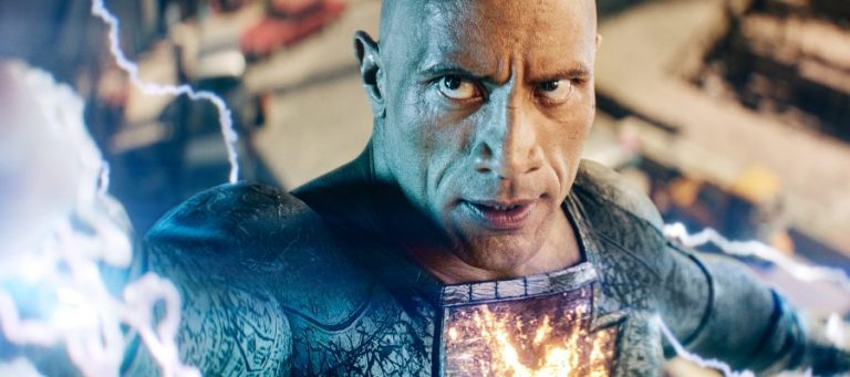 Dwayne Johnson as Black Adam looks menacingly past the camera with lightning shooting out of his hands.