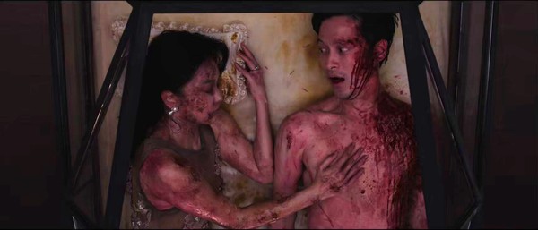Two people covered in blood lying together in a coffin in a scene from Tomb Watcher