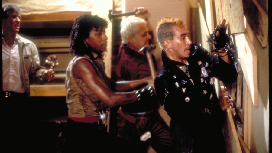 The cast of Return of the Living Dead barricading a window with wooden planks.