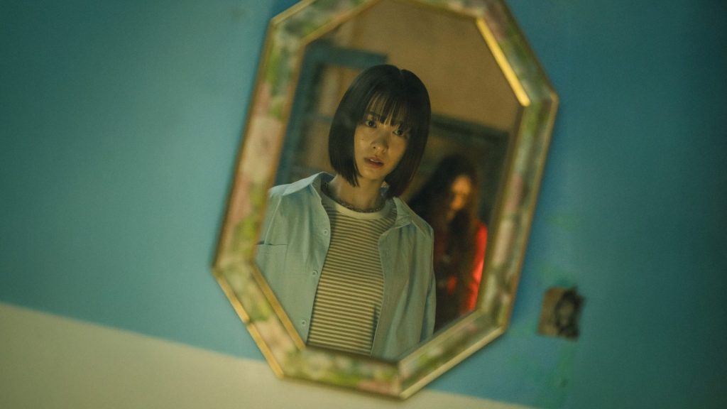 Riko looking in a mirror in a scene from The Curse