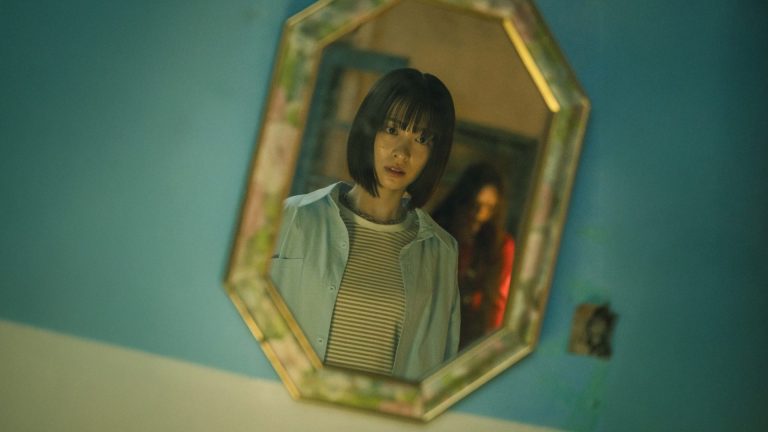 Riko looking in a mirror in a scene from The Curse