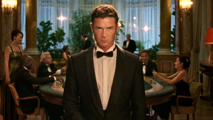 A man in a black tuxedo central in the scene staring at the camera in Reflection In A Dead Diamond