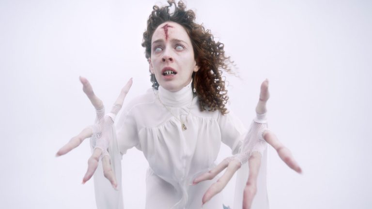 A vampire dressed all in white with blood on their head in a scene from Silencio