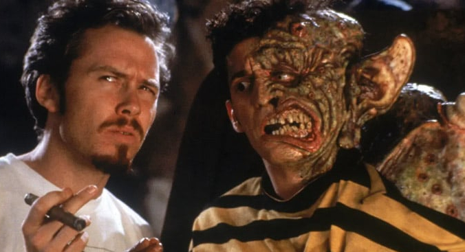 Tom Stern looks quizzical and Alex Winter has a half face of monstrous prosthetics in a scene from Freaked.