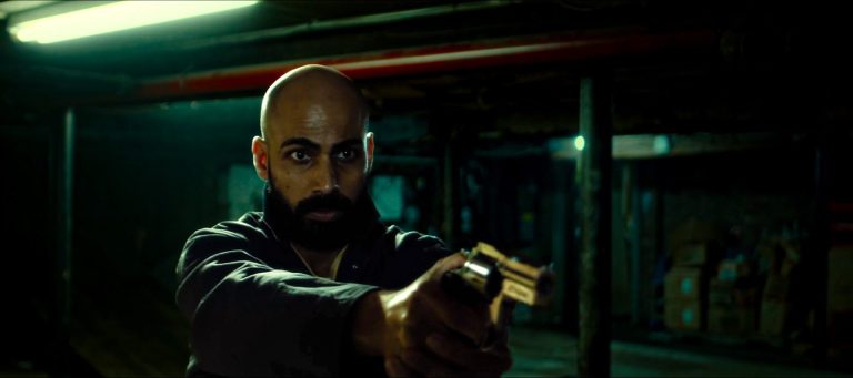 A man shooting a gun in a scene from Itch!