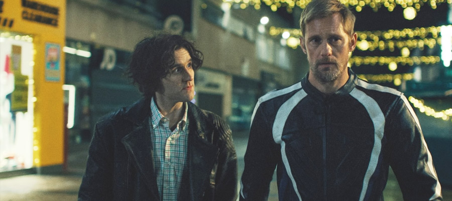 Harry Melling and Alexander Skarsgård walk through a scene in Pillion