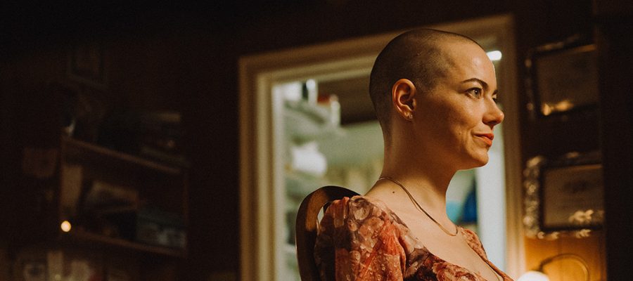 Emma Stone with shaven head staring off camera